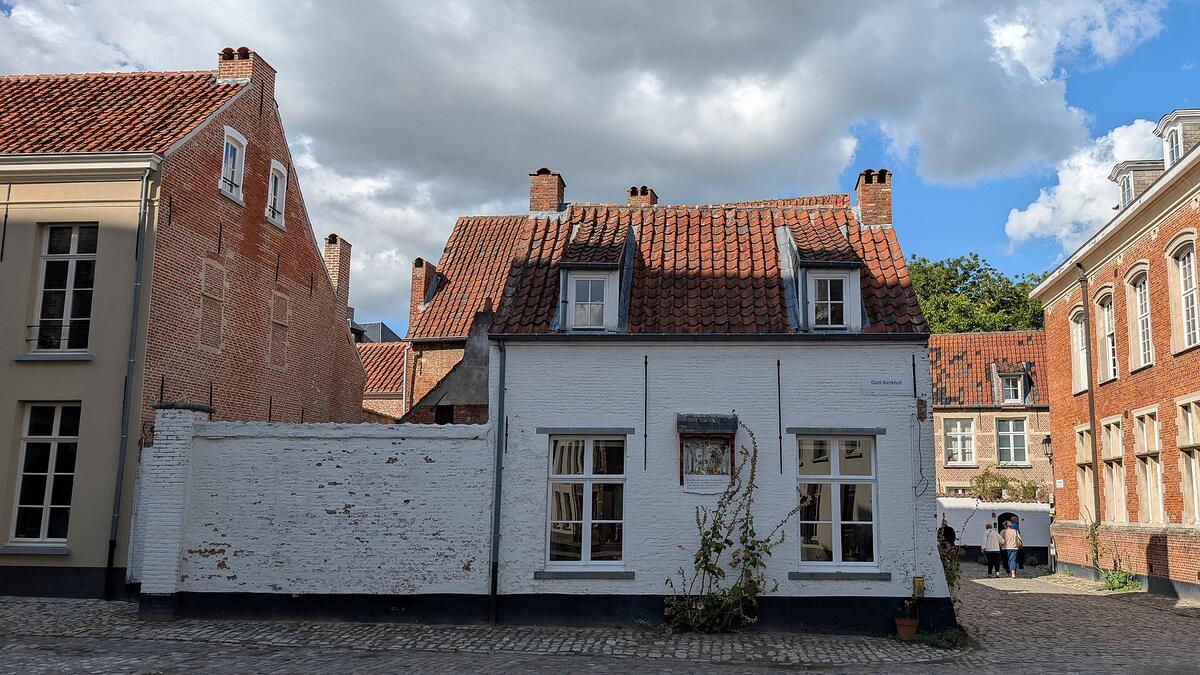 Wit geschilderd huis met rode pannen en een witte tuinmuur op een kasseiplein in het Begijnhof van Lier