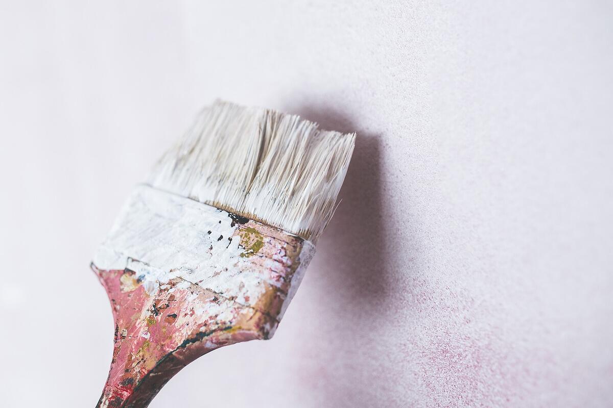 Gebruikte verfborstel met witte verf tegen een witte muur