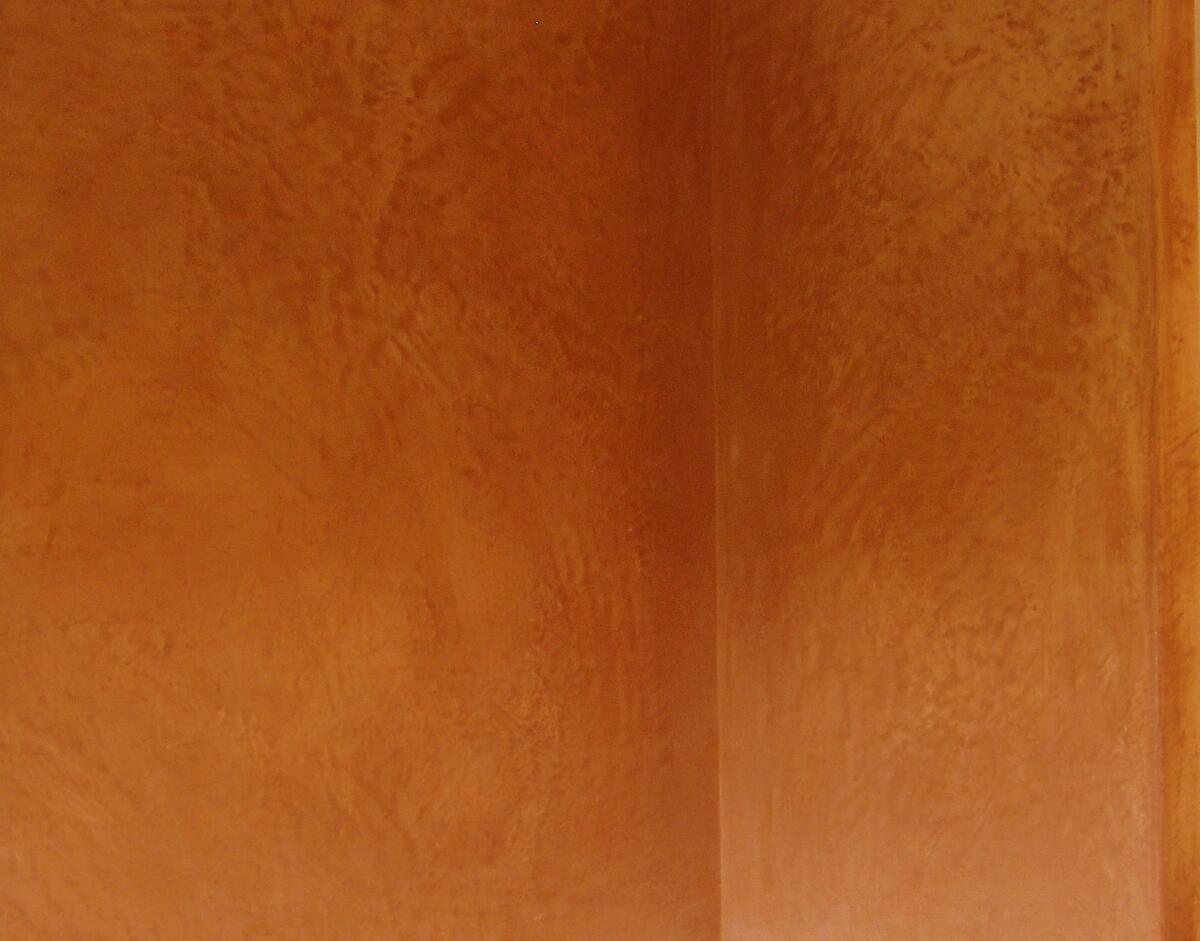 Hoek van een kamer met een warme okerkleurige kalkafwerking met wolkige tekening