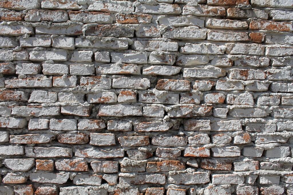 Oude baksteenmuur met een verweerde witte laag over de stenen